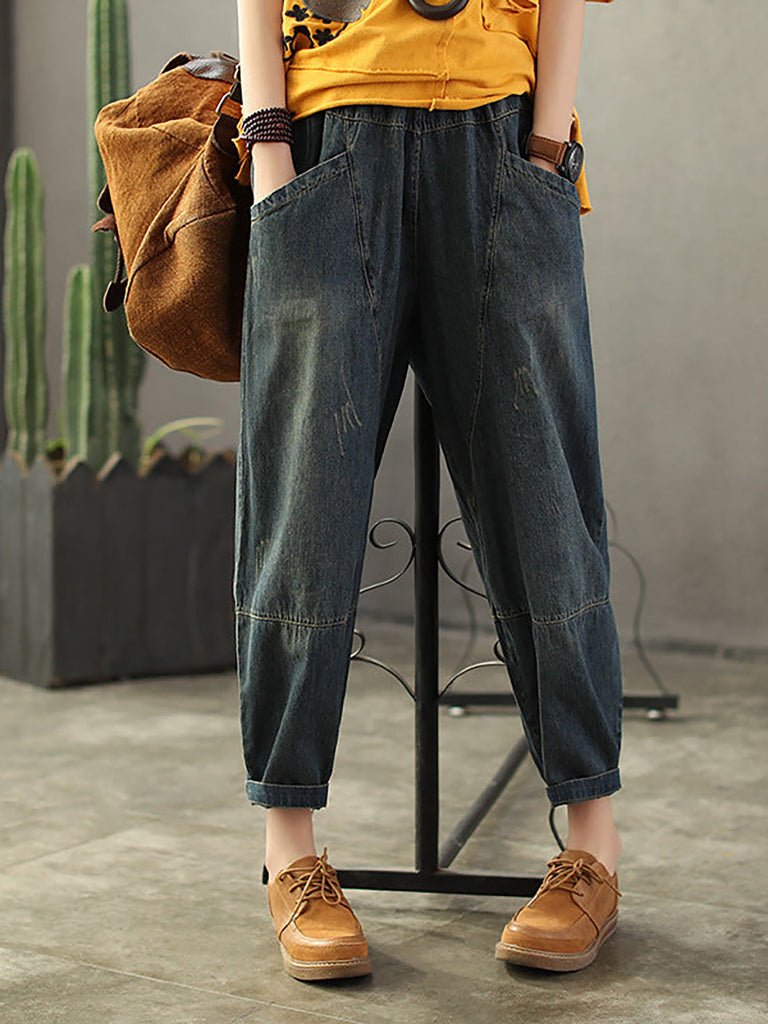 A pair of plus size vintage distressed denim jeans with an elastic waist, worn by a model standing in front of a cactus.